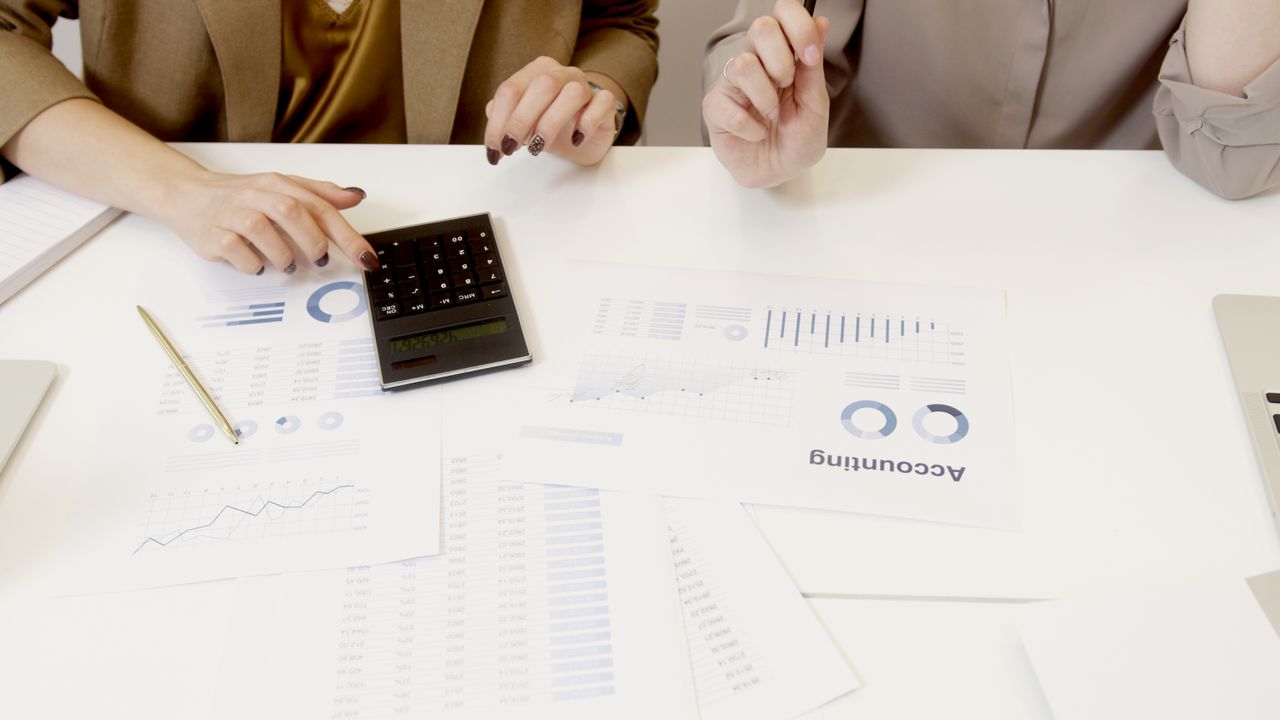 heros-img Two professionals analyzing financial documents with a calculator.